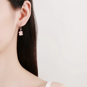 Élégantes boucles d'oreilles trèfle en or rose avec pierres roses sur mannequin