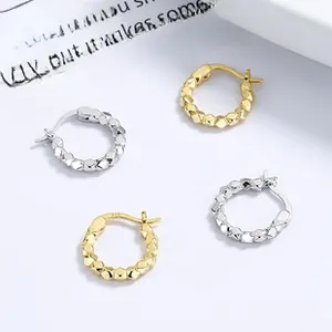 Details von geometrisch facettierten Creolen in Silber und Gold mit Metallstruktur