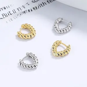 Detail showing gold and silver twisted hoop earrings with a textured spiral design