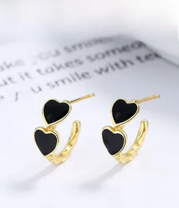 Detail of s925 silver heart hoop earrings with black enamel and golden finish