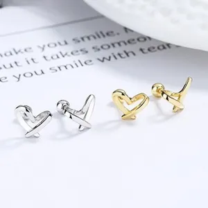Detail of interlocking heart stud earrings in gold and silver finish with ball backings