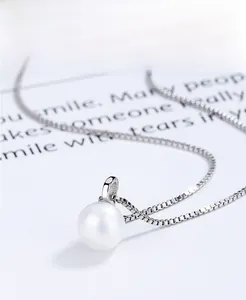 Macro d'un pendentif collier perle en argent 925 sur un fond blanc minimaliste