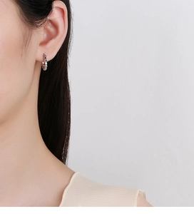 Nahaufnahme von silbernen gedrehten Creolen im minimalistischen Stil am Model