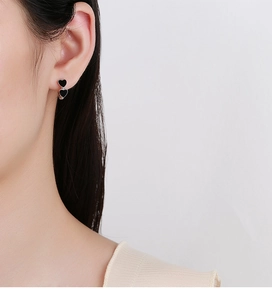 Macro close-up of 925 silver hoop earrings with dual black heart enamel charms on model