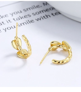 Detailed macro view of golden C-shaped hoop earrings with heart and hammered texture