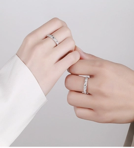 Close-up of couple holding hands wearing textured 925 silver rings with leaf patterns