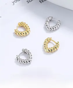 Detailed macro view of gold and silver triangular twisted rope hoop earrings set