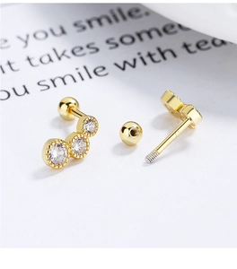 Macro shot of 925 silver gold-plated stud earring with three sparkling round zircons