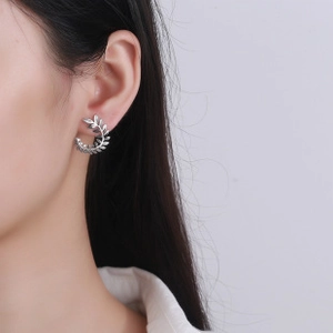 Macro detail of S925 sterling silver leaf earrings with vintage texture on model