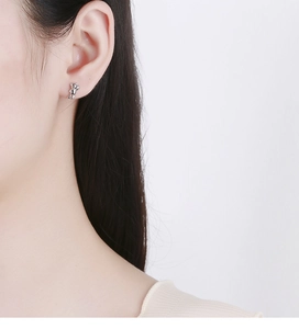 Detail view of a 925 silver bear stud earring worn by a model on the earlobe