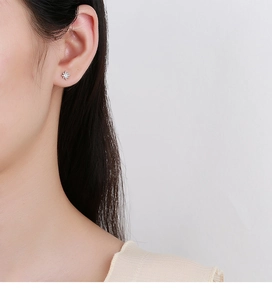 Detail of 925 sterling silver star stud earring with zircon on ear lobe
