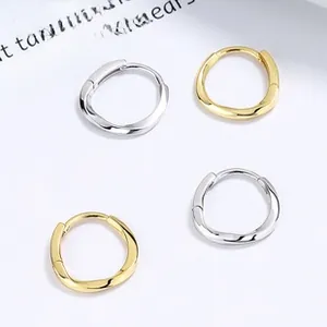 Detail of twisted 925 sterling silver hoop earrings with polished gold and silver finish