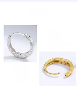 Macro detail of frosted 925 sterling silver hoop earrings in silver and gold finishes