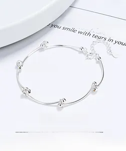 Macro shot of 925 sterling silver bean knot bracelet with hallmark tag on white paper