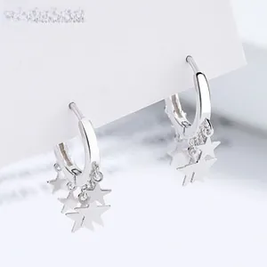 Macro shot of 925 sterling silver hoop earrings with dangling solid star charms on white background