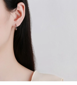 Close-up of 925 sterling silver Mobius earrings on a model ear lobe