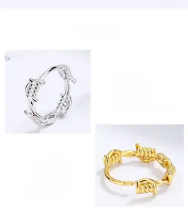 Detail showing hand polished sterling silver barbed wire hoop earrings in gold and silver