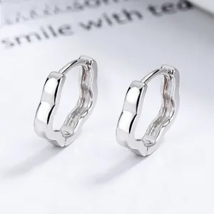 Macro shot of 925 sterling silver hoop earrings with unique wave edge and polished finish