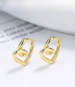 Détail macro de boucles d'oreilles cœur en argent S925 doré montrant le poinçon