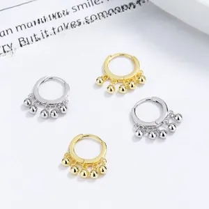 Detailed view of 925 sterling silver hoop earrings with five dangling beads in gold and silver