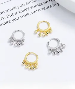 Detail of S925 sterling silver hoop earrings with five hanging metal beads in gold and silver