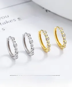 Close-up of silver and gold hoop earrings with bezel-set round cubic zirconia stones