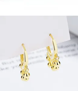 Close-up of 925 sterling silver hoop earrings with polished gold ball tassels