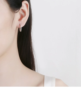 Close-up of a 925 silver twist hoop earring with sparkling pavé zircon on a model's ear