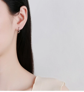 Détail de boucles d'oreilles créoles en argent 925 avec cœurs entrelacés sur mannequin