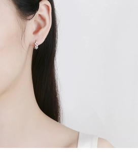 Detail of 925 sterling silver leaf hoop earring with sparkling zircon on model ear