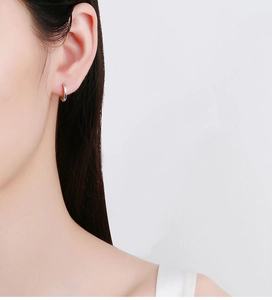 Gros plan d'une boucle d'oreille créole minimaliste en argent 925 portée par une femme