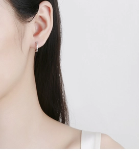 Close-up of a 925 sterling silver hoop earring with clear cubic zirconia on ear