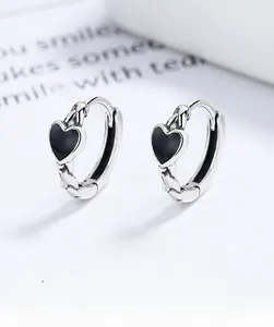 Close-up of 925 sterling silver hoop earrings with black enamel heart charms and braided texture