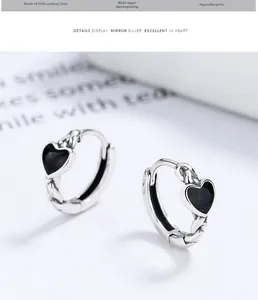 Macro detail of S925 sterling silver hoop earrings with black enamel heart accents