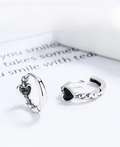 Macro detail of 925 sterling silver heart hoop earrings with black enamel and woven texture