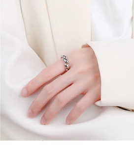 Detail of silver twisted rope ring worn by a model against a white blazer backdrop