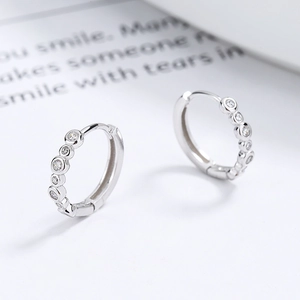 Elegant 925 sterling silver hoop earrings with round clear zircons on a white background