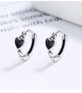 Macro shot of vintage silver heart hoop earrings with woven texture and black heart detail
