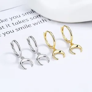 Macro shot of polished silver and gold crescent moon dangle earrings on a card