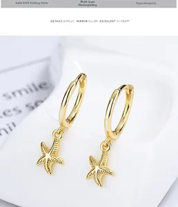Detailed close-up of gold plated 925 sterling silver starfish hoop earrings on a tray