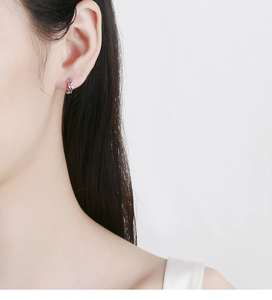 Close-up of 925 sterling silver Mobius hoop earring worn by a model in a side view