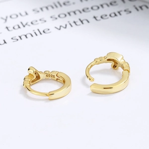 Minimalist 925 sterling silver gold huggie hoop earrings on printed paper background