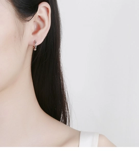 Macro shot of 925 sterling silver chain link hoop earrings on model ear lobe