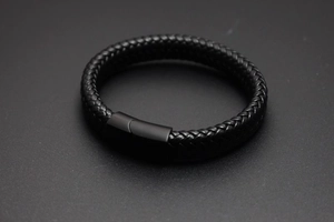 Gros plan d'un bracelet en cuir tressé noir avec un fermoir magnétique en métal mat