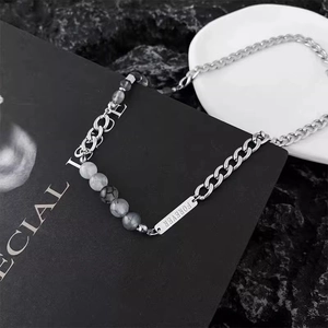 Detailed macro view of silver titanium steel necklace with marble beads and FOREVER tag