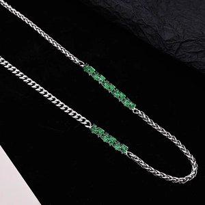 Macro shot of a silver chain necklace featuring emerald-green zircon in a rectangular cut