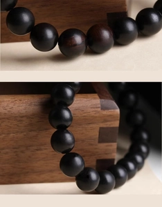 Macro shot of polished black ebony beads showing natural wood grain and zen aesthetic