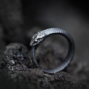 Macro shot of retro Ouroboros ring with detailed snake scale texture on stone background
