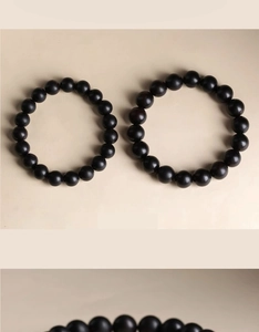 Detail of minimalist men's matte black beaded bracelets in various bead sizes