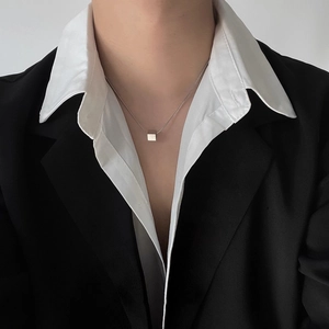 Close-up of minimalist silver cube pendant necklace worn with a suit for men